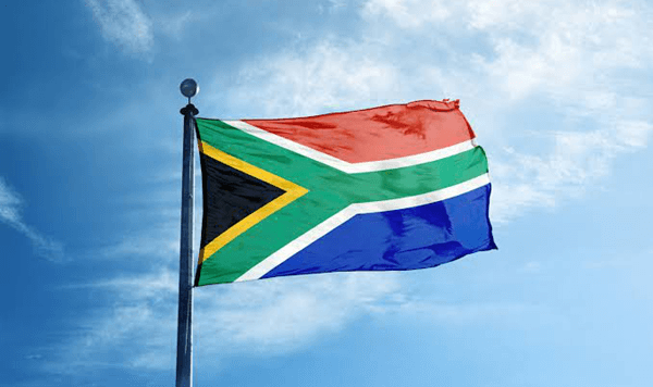 Which country's flag features a unique 'Y' shape consisting of green, yellow, and black, with a red triangle and white border?
