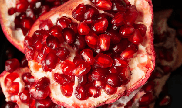 Which winter fruit has a tough red skin filled with hundreds of juicy, jewel-like edible red seeds inside?