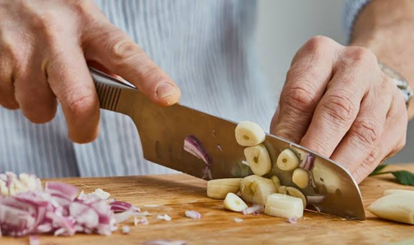 What simple physical trick removes stubborn garlic or onion odors from your hands after chopping?