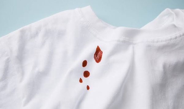 When dealing with fresh blood or dairy stains on clothing, what water temperature and method should you use to prevent setting the stain?
